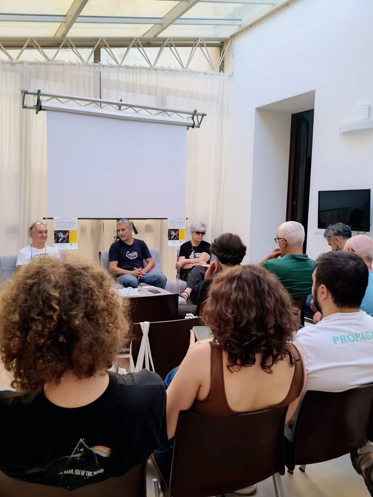 Persone di spalle sedute in una sala, mentre ascoltano i relatori durante la presentazione del libro “Israele Palestina – No al genocidio, sì alla soluzione binazionale”.
