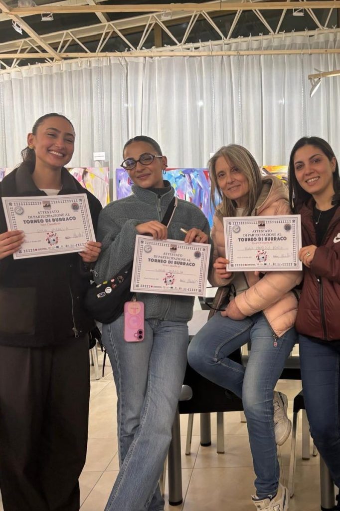 Quattro persone in posa, ciascuna con un attestato in mano, durante una cerimonia di consegna.