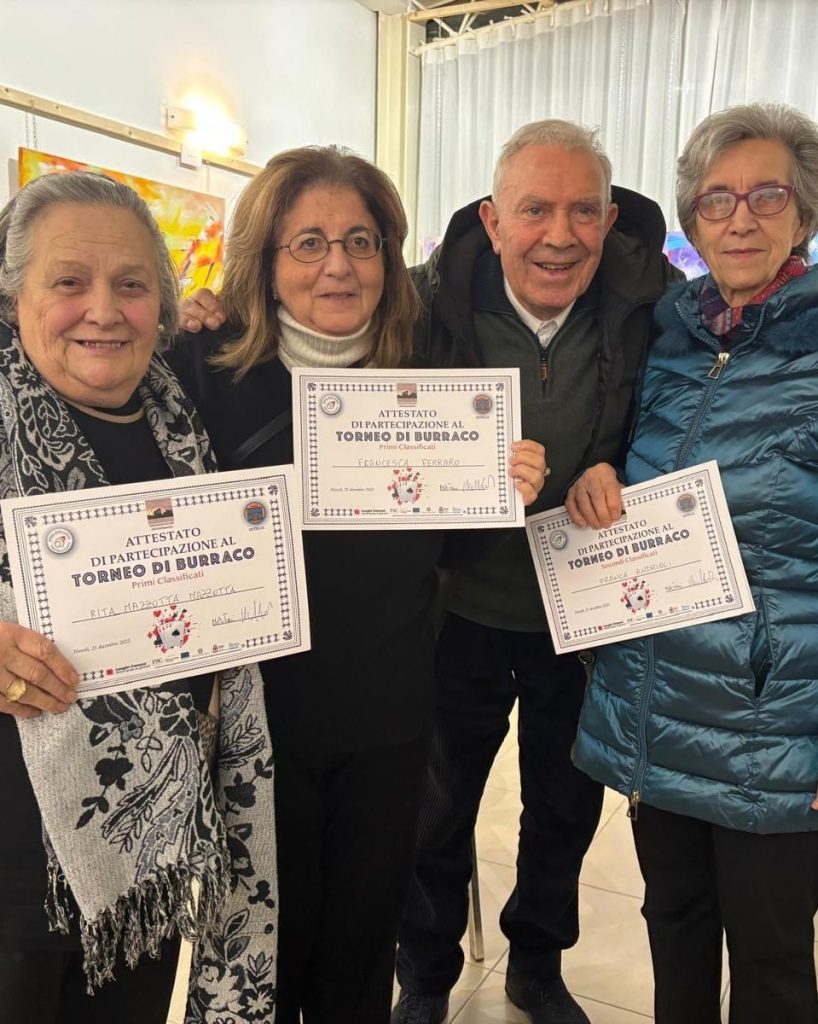 Quattro partecipanti tengono in mano gli attestati del torneo di burraco, riuniti per una foto di gruppo.