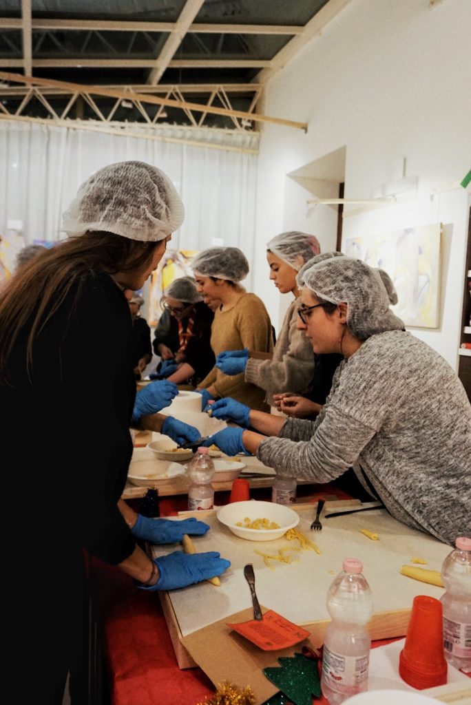 Un gruppo di persone giovani lavora insieme a un tavolo durante un laboratorio organizzato con l’associazione Nodi.